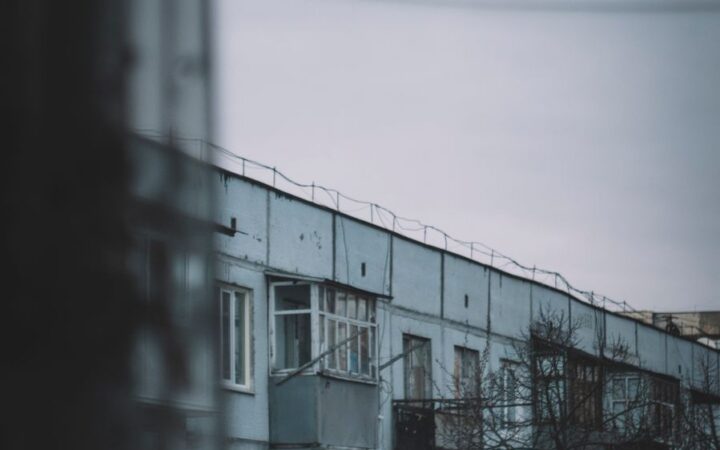 Настроенческий вид на городской жилой блок через окно в облачный день, запечатлевающий созерцательную городскую сцену.