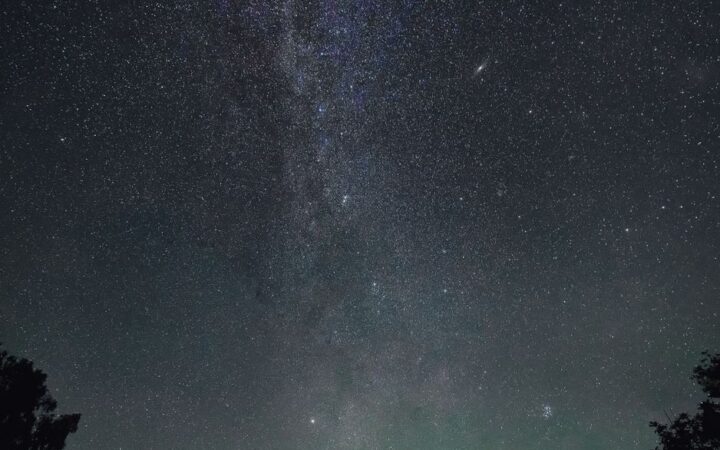 Старый дом под обширным ночным небом, полным звезд и великолепием галактики.